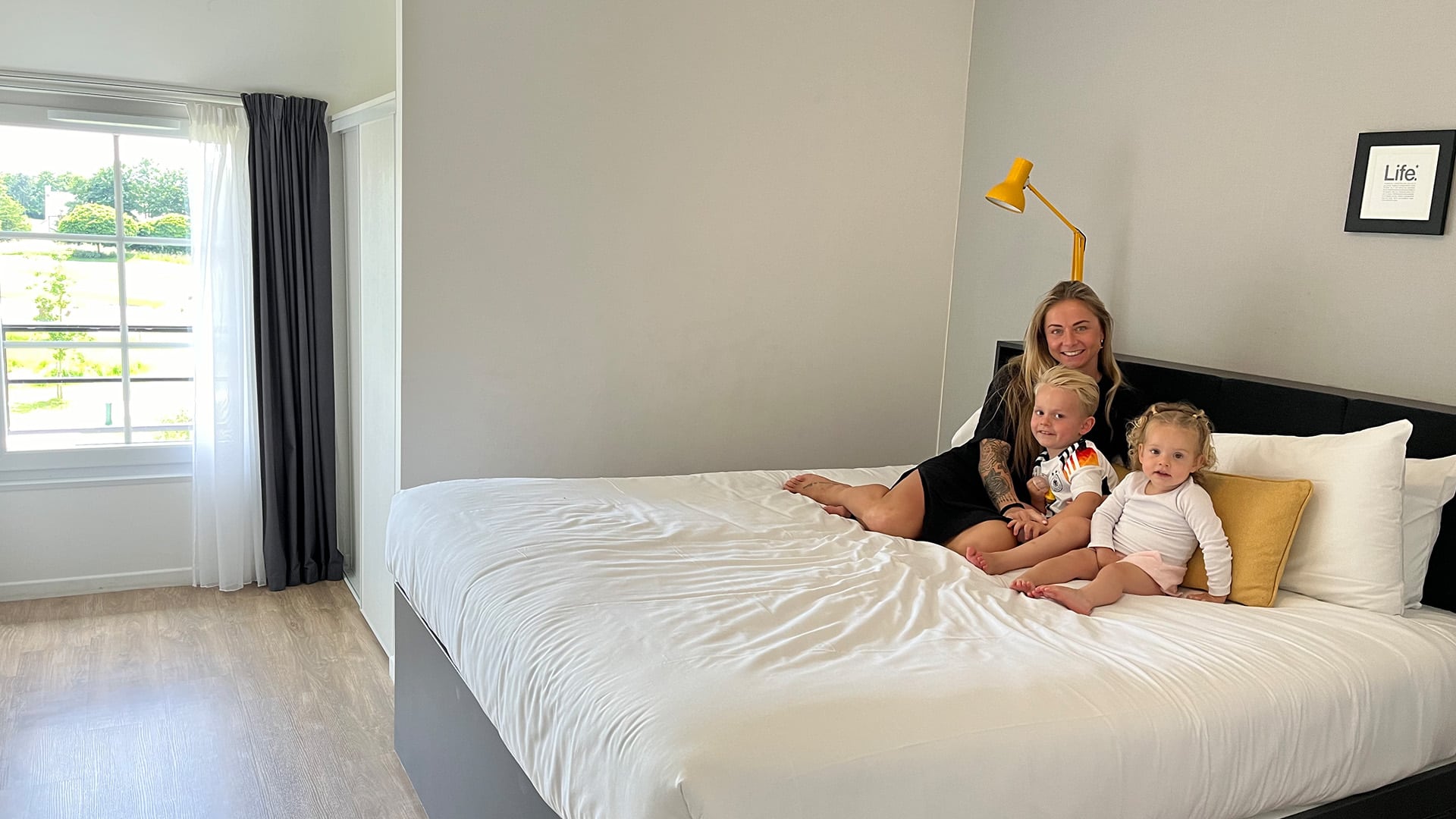 Tatjana ontspant met haar twee jongste kinderen op het bed van hun hotelkamer na aankomst.