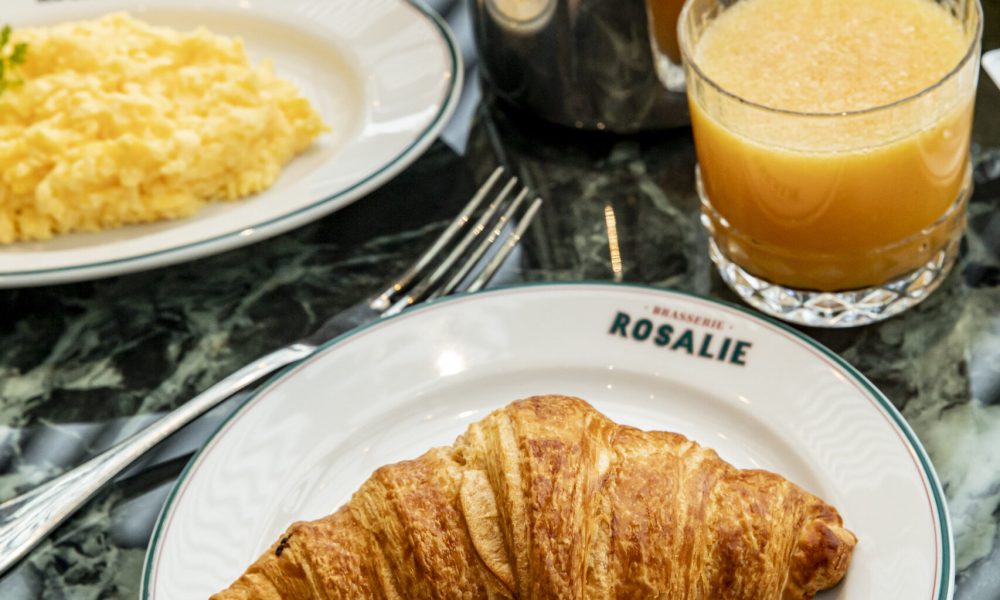 Het 'Express'-ontbijt van Brasserie Rosalie met een verse croissant, cappuccino en een glas jus d'orange op tafel.
